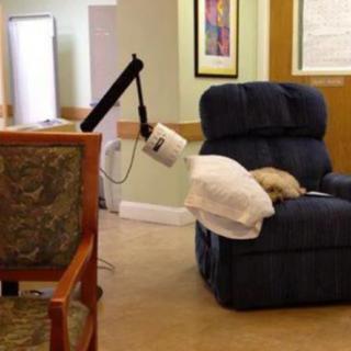 A healthcare robot in a nursing home setting, positioned near a recliner chair.