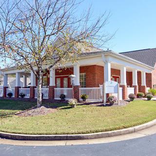 A suburban house with a large porch and landscaped yard.