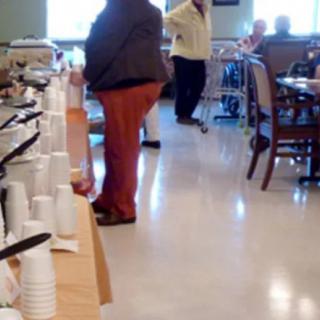 People in a dining room setting with a buffet table and seating area.