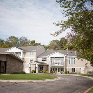 A suburban residential building surrounded by trees with a driveway in the foreground.