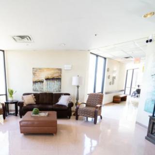 A modern living room with a sofa, armchairs, and large windows.