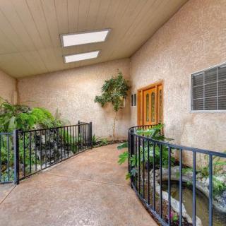 A peaceful indoor atrium featuring a walkway surrounded by lush plants and a small pond, illuminated by natural light from skylights.