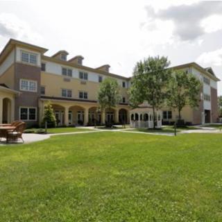 A residential apartment building with a well-maintained lawn and surrounding trees.