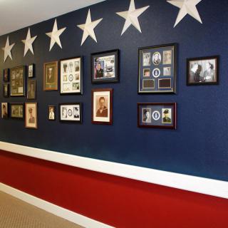 A wall decorated with military memorabilia and photographs, featuring a patriotic color scheme with stars.