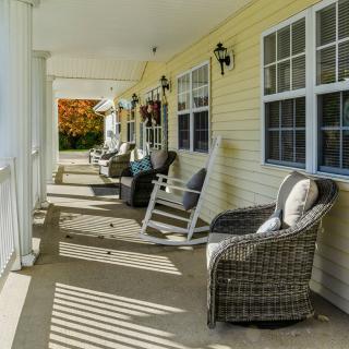 A peaceful porch with wicker chairs and a rocking chair, perfect for relaxing in the autumn afternoon.