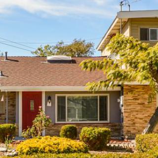 A suburban house with a manicured front yard under a sunny sky.