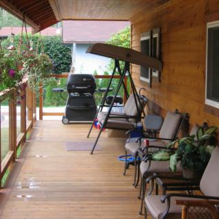A cozy wooden porch with outdoor furniture and plants.