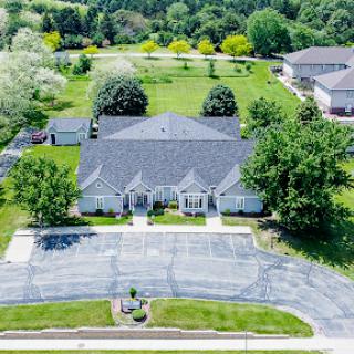 Aerial view of a spacious home surrounded by lush greenery and well-maintained grounds.