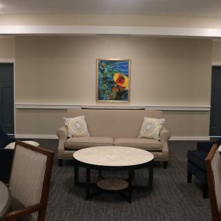 A cozy, modern living room with a sofa, coffee table, and framed artwork on the wall.