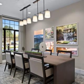 A modern dining room with elegant lighting and framed artwork on the walls.