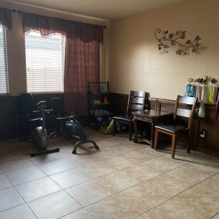 A room with exercise equipment, a table with chairs, and decorative elements.