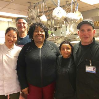 A diverse team of chefs and kitchen staff posing together in a restaurant kitchen.