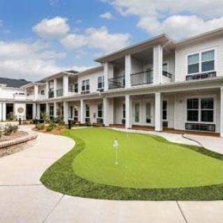 A modern residential building with a landscaped outdoor area, featuring a golf putting green.