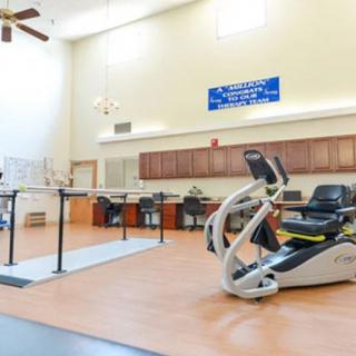 A rehabilitation facility with exercise equipment and parallel bars for physical therapy.