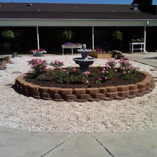 A beautifully landscaped circular garden featuring flowers and a central fountain.