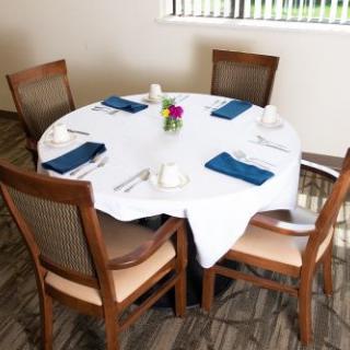 A neatly set dining table with four chairs and a decorative centerpiece.