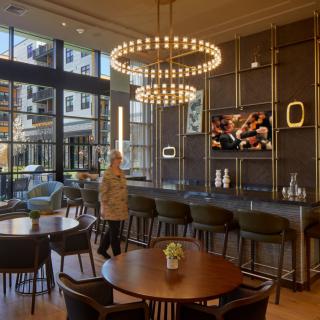 A modern restaurant interior featuring elegant chandeliers and a stylish bar area with comfortable seating.