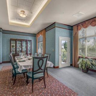 An elegant dining room with a set table and chairs, featuring blue walls and large windows.