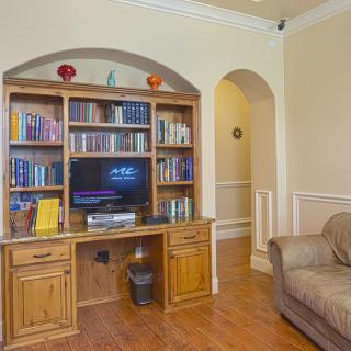 A cozy living room featuring a wooden bookshelf with books and a television, alongside a comfortable sofa.