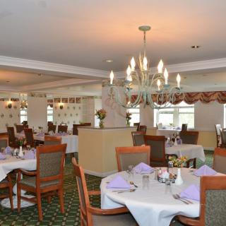 An elegant dining room with neatly arranged tables and a chandelier.
