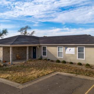 A small clinic or office building with a driveway and sparse landscaping under a partly cloudy sky.