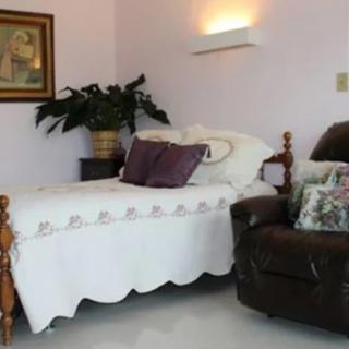 A cozy bedroom corner with a bed, armchair, and decorative elements.