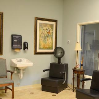 A salon waiting area featuring chairs, a sink, wall art, and a hair dryer.