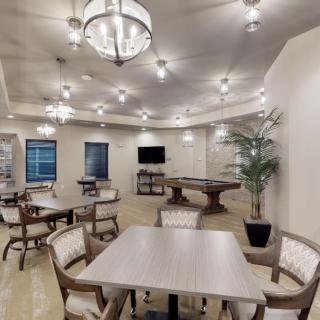 A modern lounge area featuring tables and chairs, a pool table, and a wall-mounted TV.
