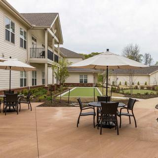 A well-maintained patio area with umbrella-covered tables at a residential apartment complex.