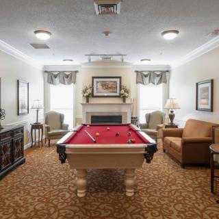 A cozy recreation room featuring a billiard table and comfortable seating around a fireplace.