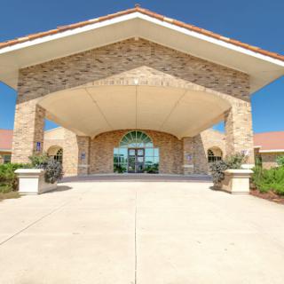 A welcoming entrance to a beautifully designed building, showcasing modern architecture against a clear blue sky.