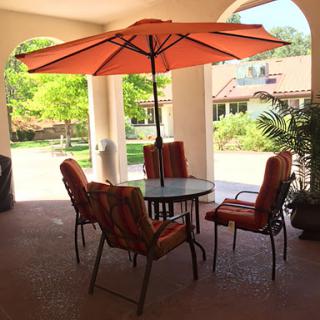 A cozy outdoor seating area featuring a table with an umbrella and colorful chairs, perfect for enjoying the fresh air.
