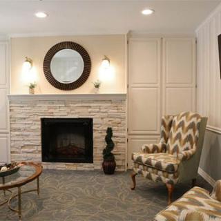 A cozy living room with a fireplace, mirror, and stylish armchairs.