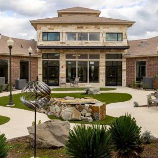 A modern building with a landscaped courtyard featuring pathways and ornamental plants.