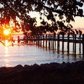 A serene sunset view from a wooden pier, reflecting on calm waters.