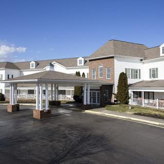 A large commercial building with an entrance and driveway under a clear blue sky.