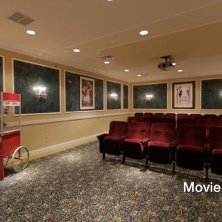 A cozy home theater setup with red seating, movie posters, and a popcorn machine.