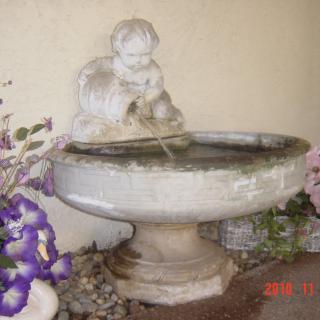 A decorative garden fountain with a statue of a child pouring water.