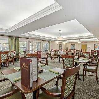 A well-lit dining room with neatly arranged tables and chairs, featuring menus on the tables.