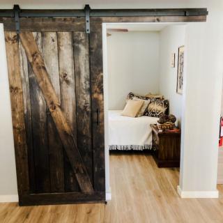 A cozy bedroom with a rustic wooden barn door entrance.
