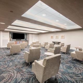 A modern lounge area featuring comfortable armchairs and a large television screen.