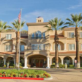 A building with palm trees and an entrance featuring an American flag.