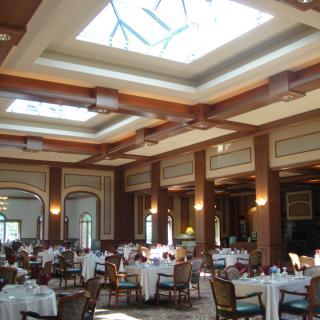 An elegant dining area with tables set and a skylight overhead.