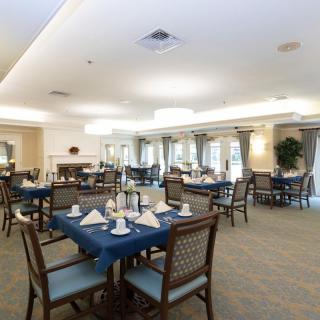 A well-lit dining room with neatly arranged tables and chairs, set for a meal.