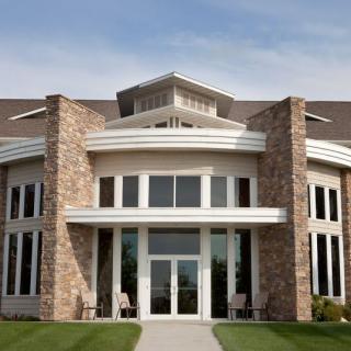 A modern building facade with large windows and stonework accents.