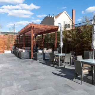 A modern outdoor dining space featuring a spacious patio with tables and chairs, perfect for enjoying meals in the sunshine.