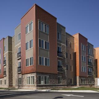 A modern apartment building with a brick facade and multiple stories, located in an urban area.