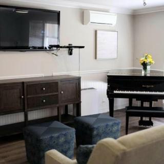A modern living room featuring a piano and a wall-mounted television.