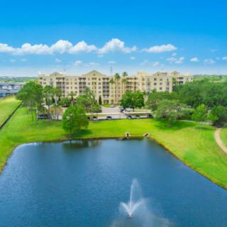 A scenic view of a large building complex by a lake with a fountain.