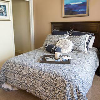 A neatly arranged bedroom with patterned bedding and a decorative tray on the bed.